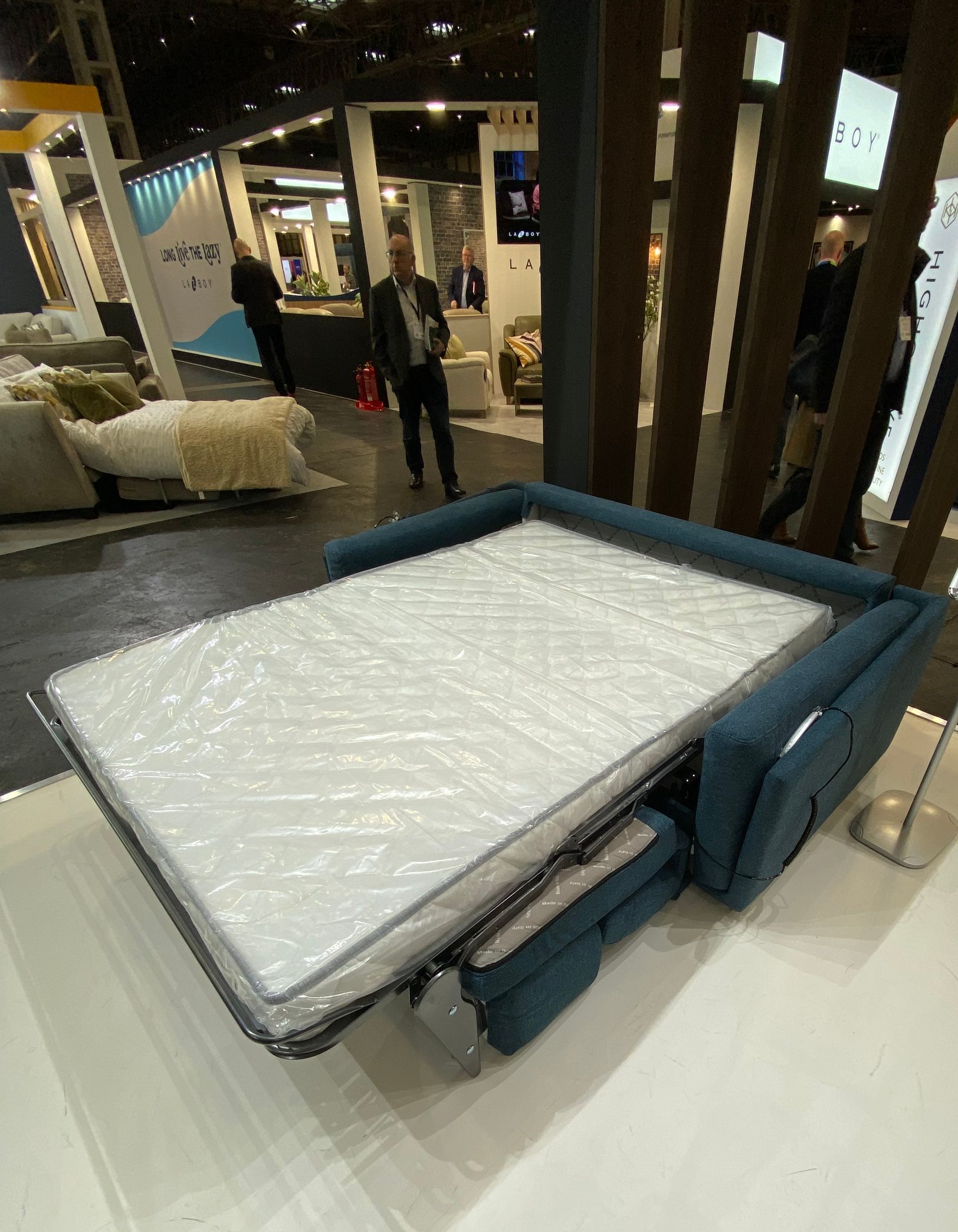 a luxury manual blue faux suede double sofa bed with a white mattress in a protective cover made in Italy at the January Furniture Show 2024, NEC, Birmingham