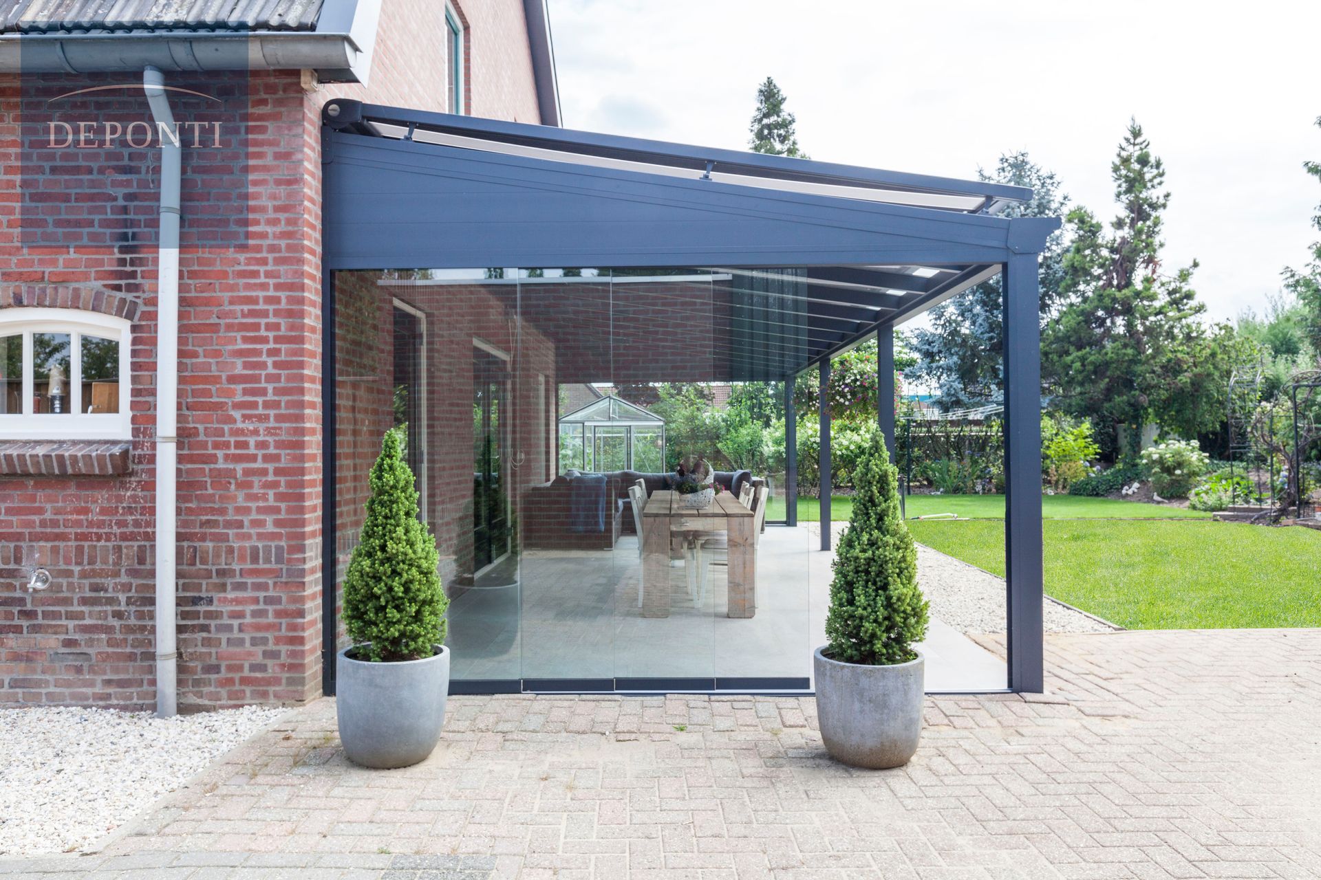 Premium Deponti aluminium veranda with glass sliding panels to the side and front and a table and chairs under the canopy