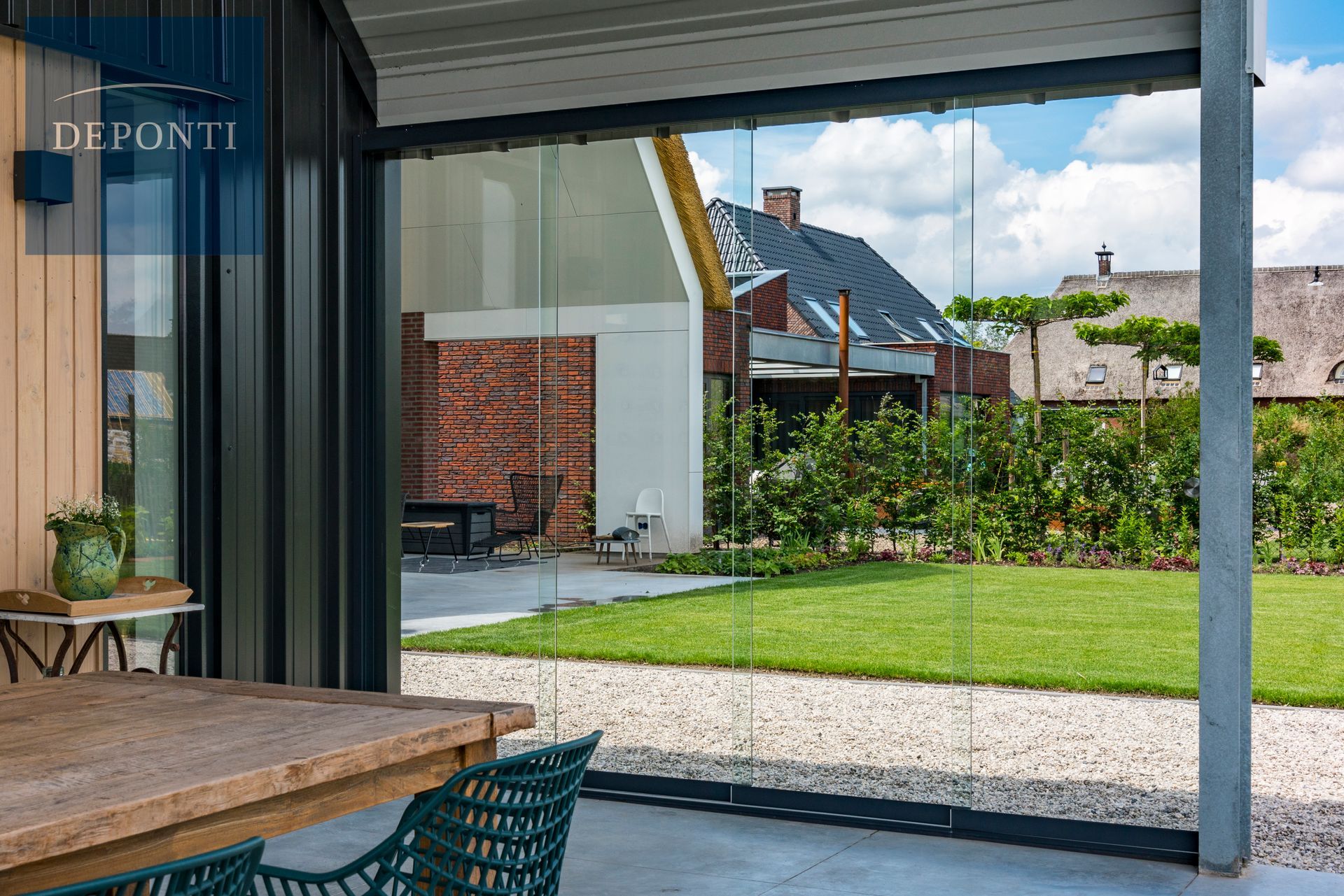 Premium Deponti aluminium veranda with glass sliding panels to the side and front and a table and chairs under the canopy