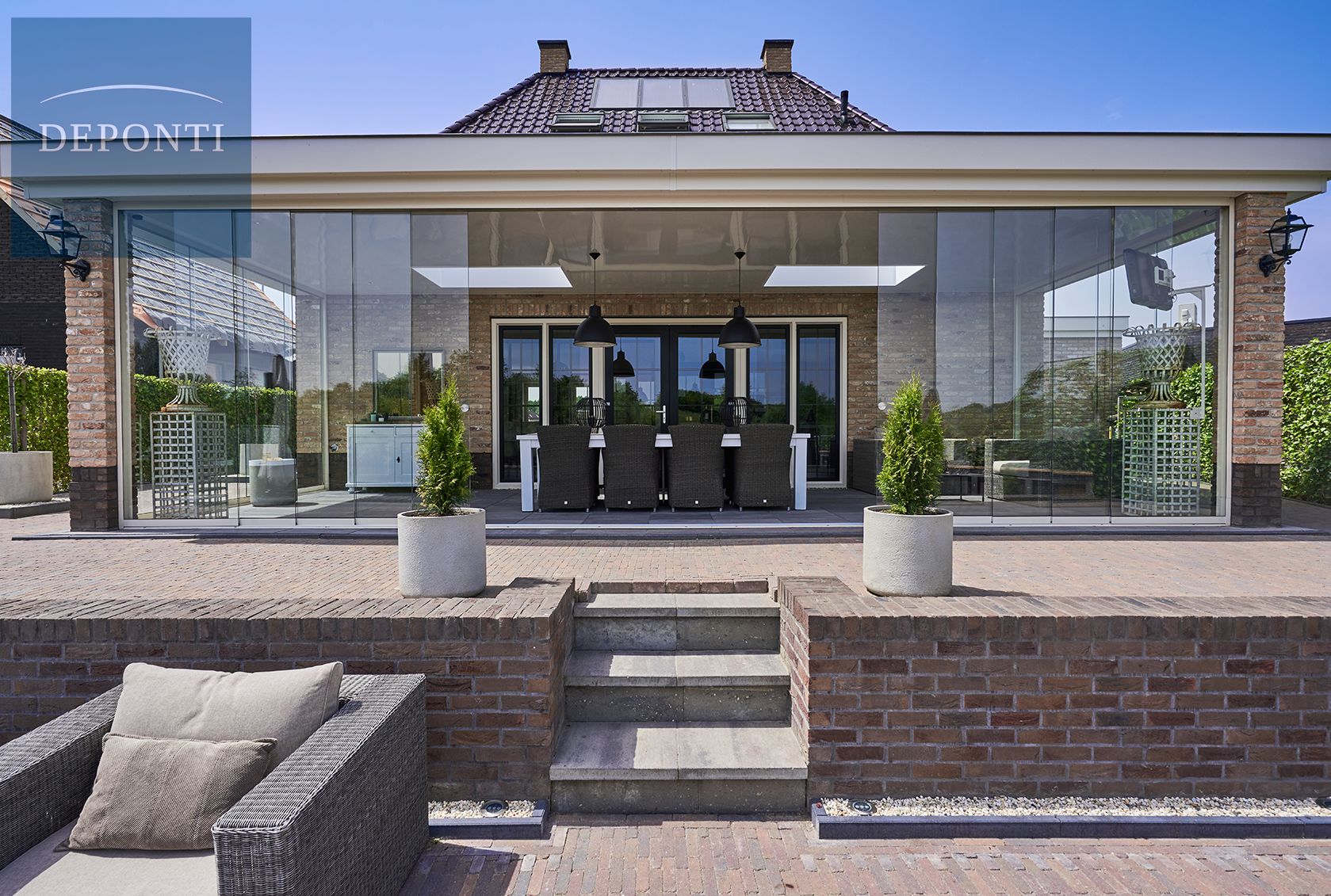 Premium Deponti aluminium veranda with glass sliding panels to the side and front and a table and chairs under the canopy