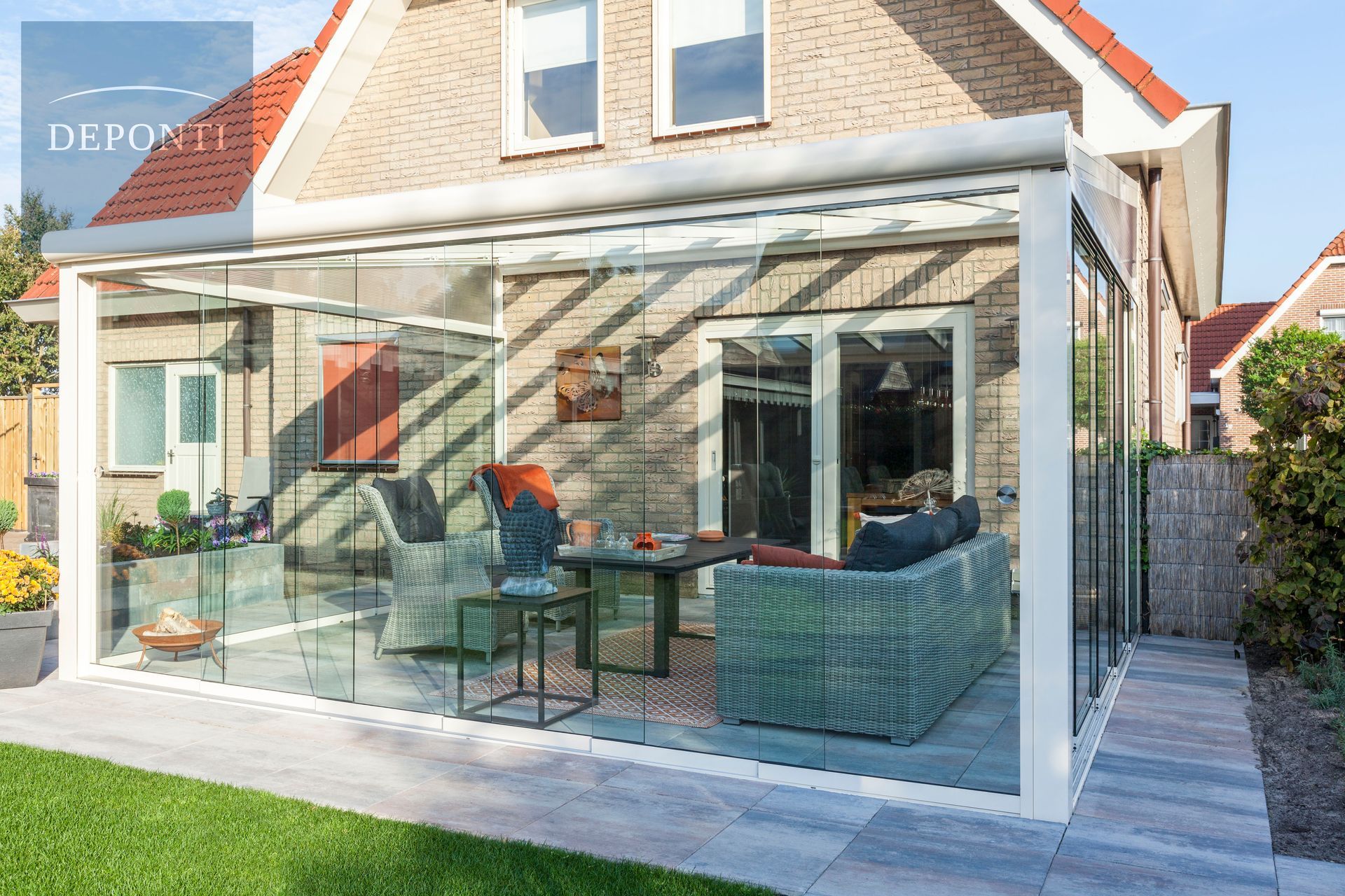 Deponti aluminium veranda with glass sliding panels to the side and front and a table and chairs under the canopy