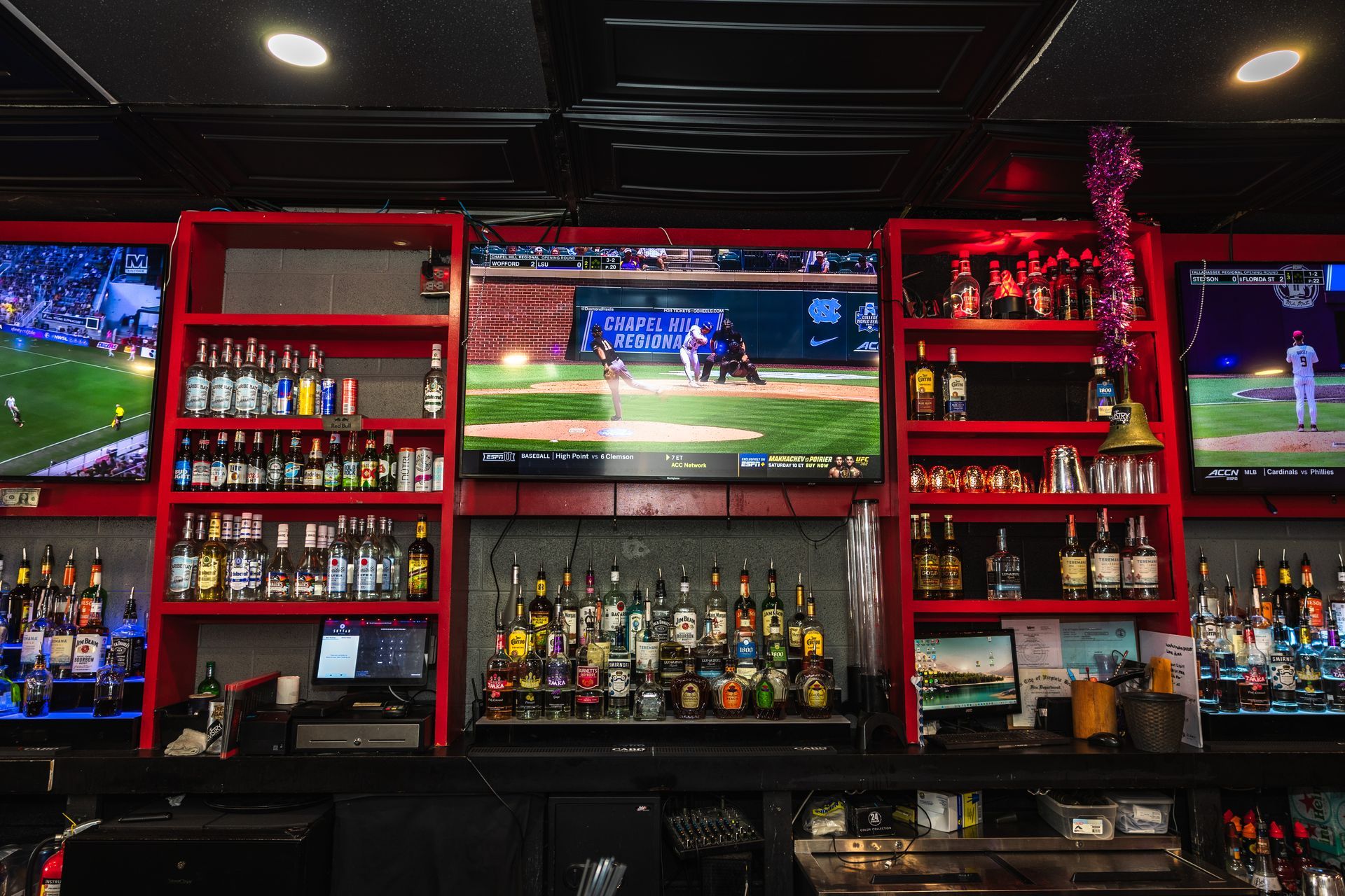 A bar with a lot of televisions and bottles of liquor.