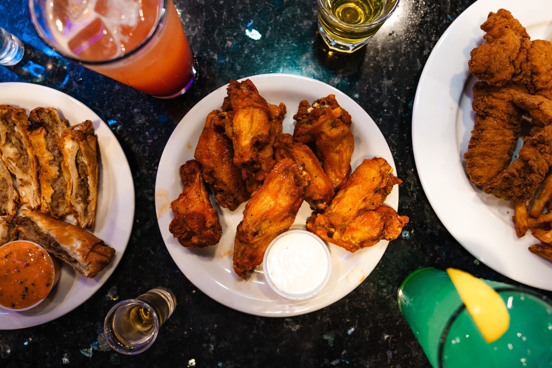 A table topped with plates of food including fried chicken wings