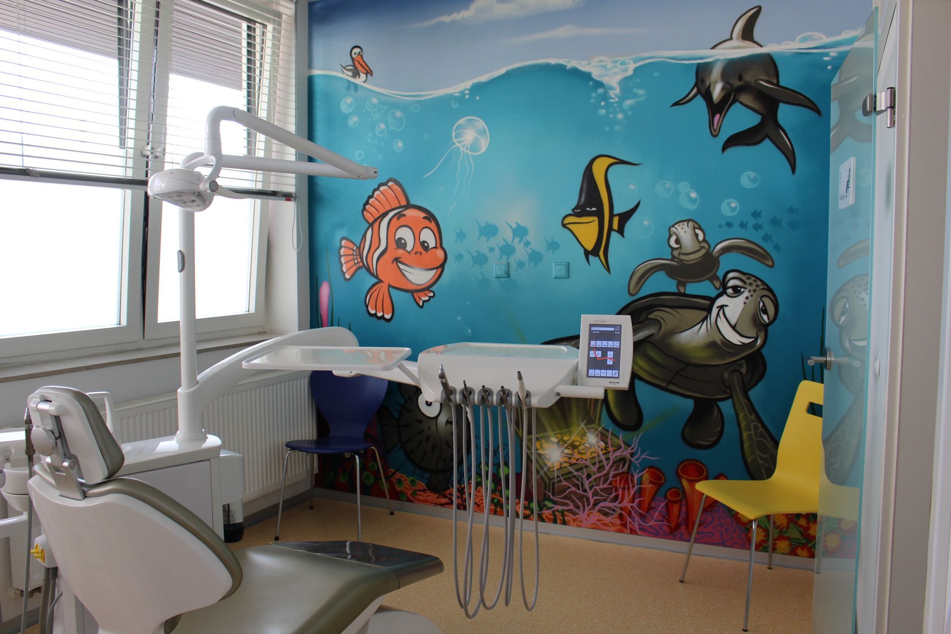 Eine Zahnarztpraxis mit einem Wandgemälde von Fischen und Schildkröten an der Wand.