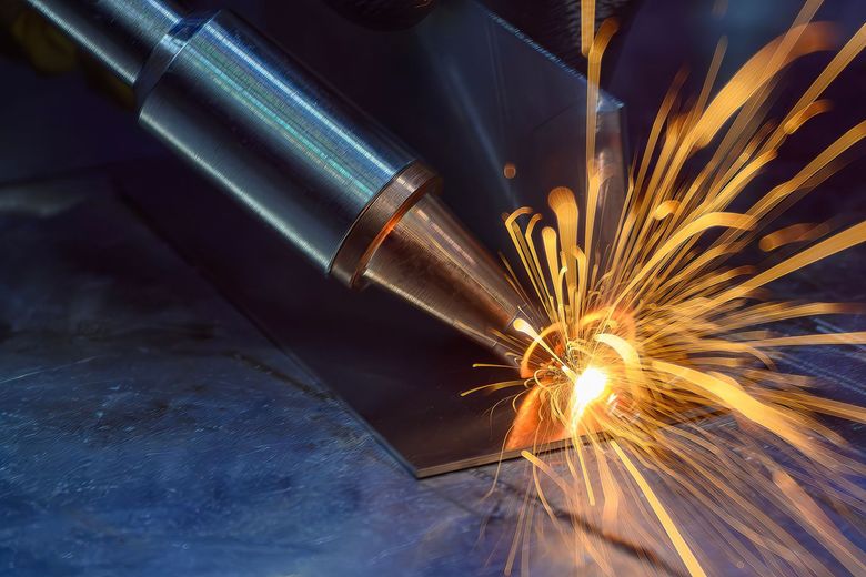 Laser cutting metal, orange sparks flying.