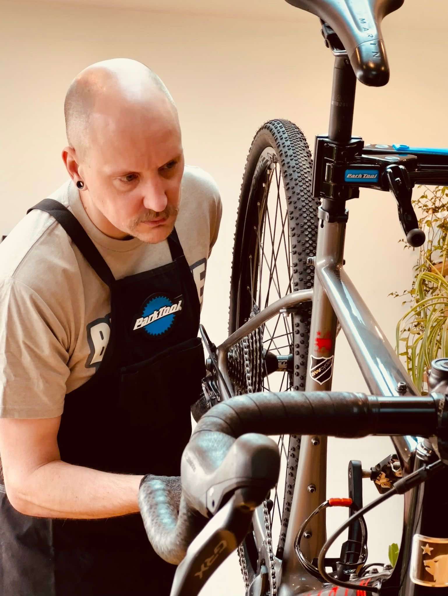 A man wearing an apron is working on a bicycle.