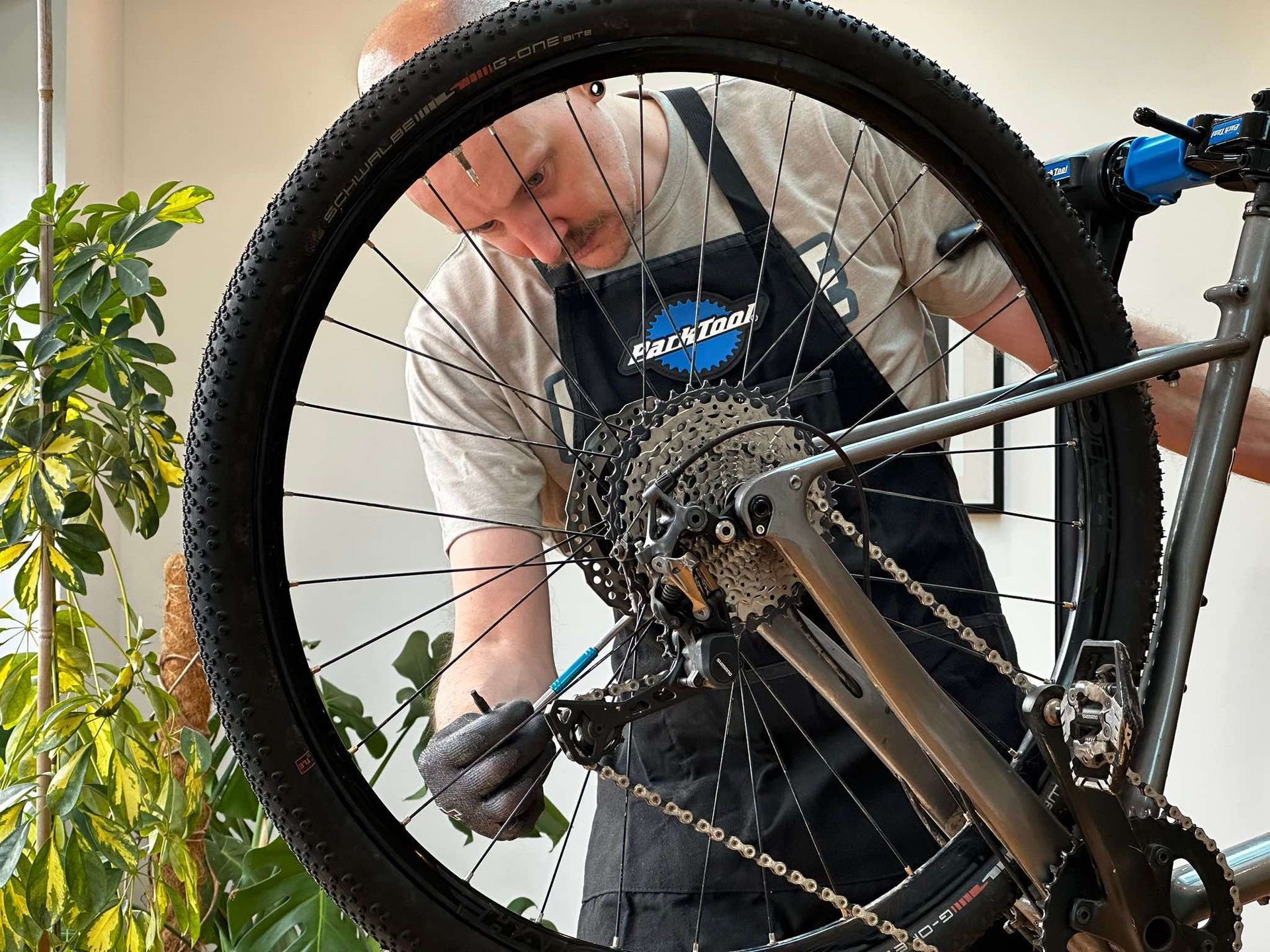 A man wearing an apron is working on a bicycle.