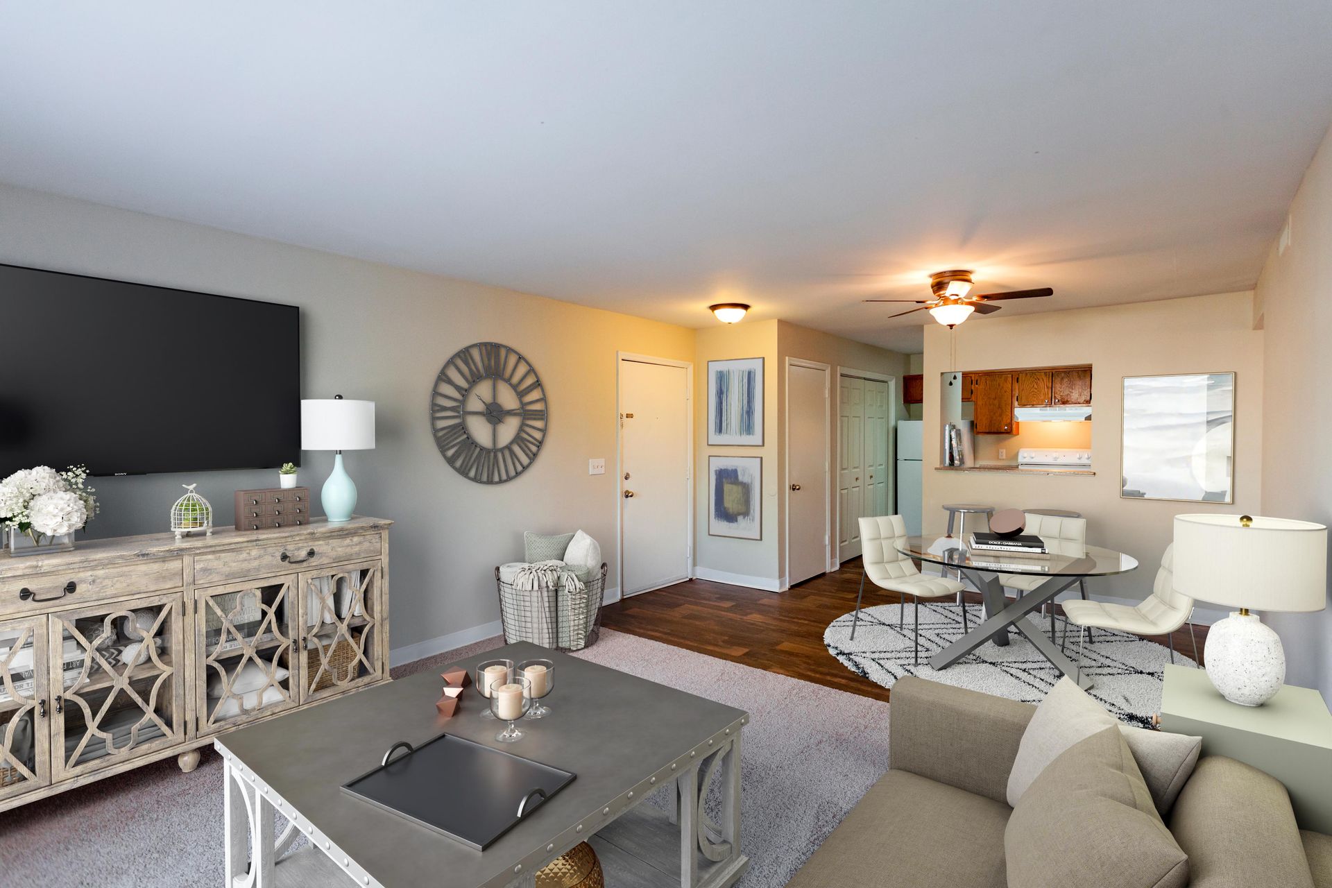 A living room with a large TV, white ornate console, gray coffee table, and a dining area with a round table and chairs.