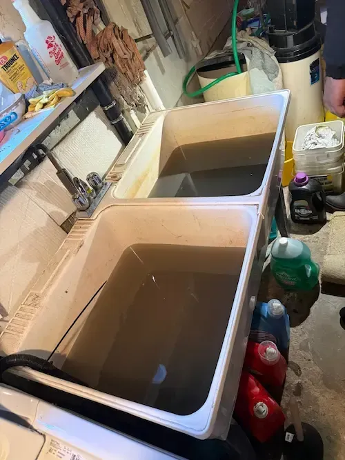 emergency plumber oakville clearing clogged laundry sink with standing dirty water