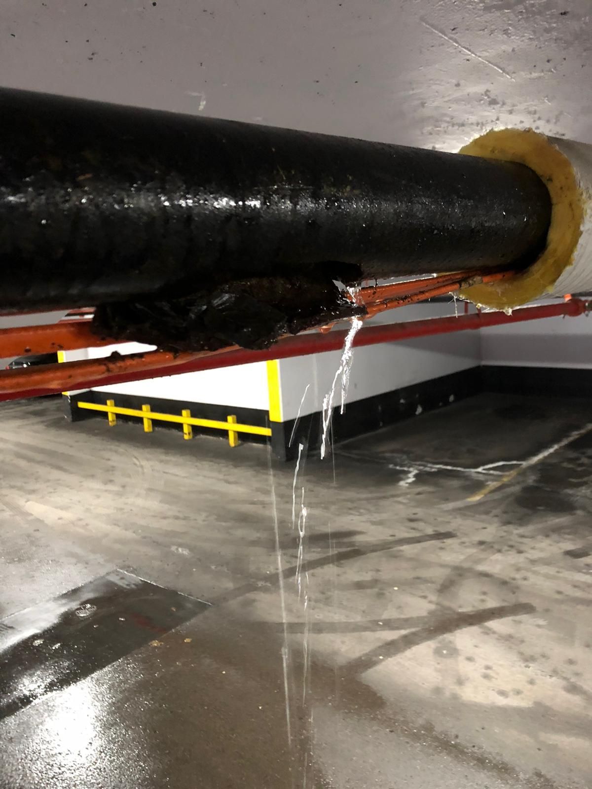 A pipe is leaking water in a parking garage