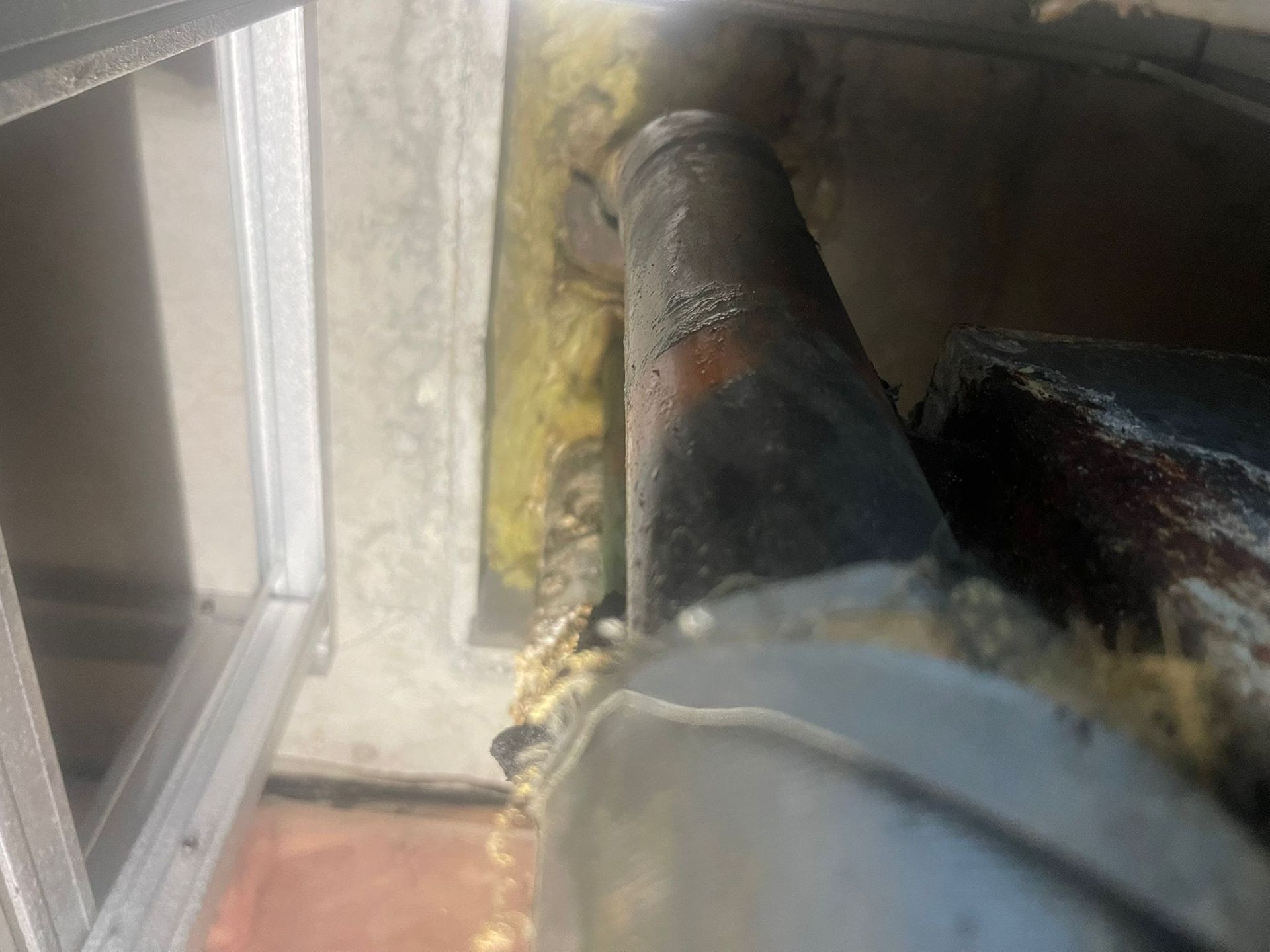 A close up of a pipe in the ceiling in a condominium building. Pipe is leaking.
