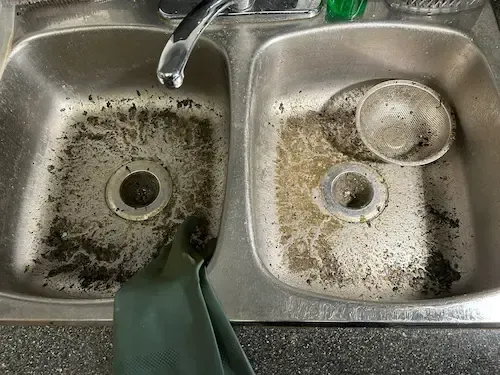 severe grease and debris buildup inside kitchen sink drain showing cause of clog in Oakville kitchen