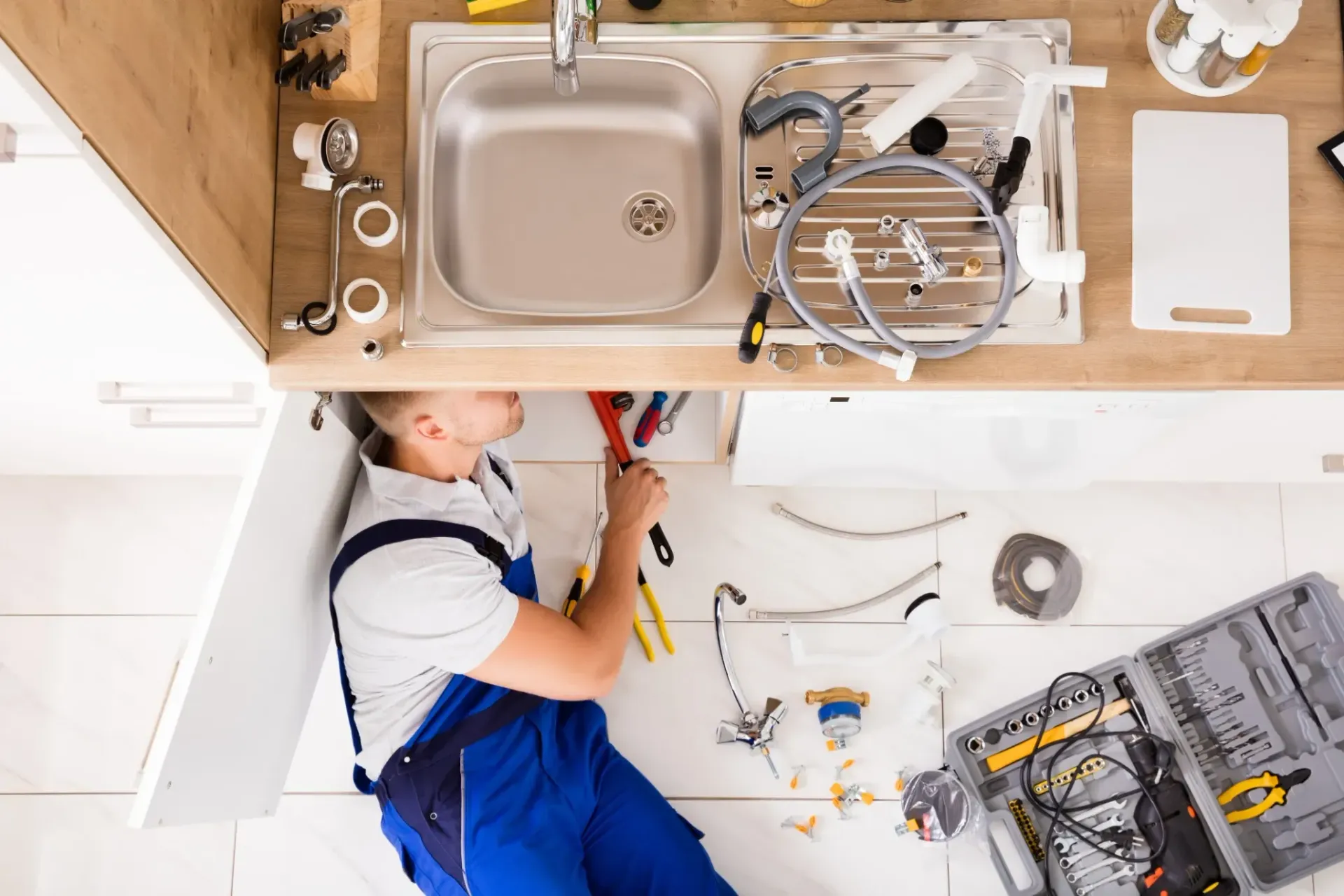 A plumber is fixing a sink in a kitchen.
