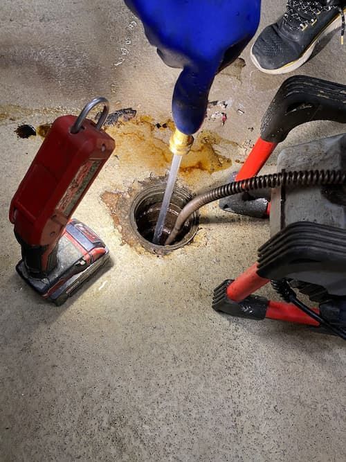 Technician from 17 Plumbing performing powerflushing with a hydro-jetting machine to clear clogged drains.