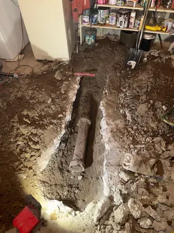 Cracked and clogged underground sewer pipe exposed during basement drain repair in Oakville