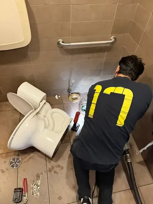 Emergency plumber Oakville technician clearing an overflowing toilet blockage in a bathroom.