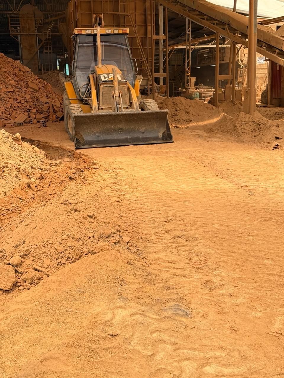 Una excavadora empuja tierra dentro de una instalación de almacenamiento de astillas de madera.
