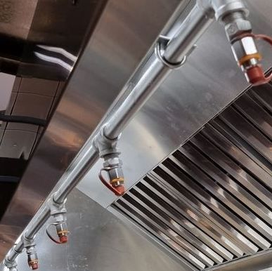Stainless steel ventilation hood with pipes and nozzles in an industrial kitchen