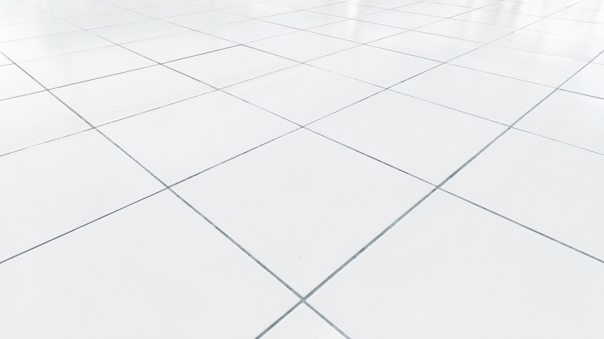 Gloved hand wiping grout between white floor tiles on a marble-look surface