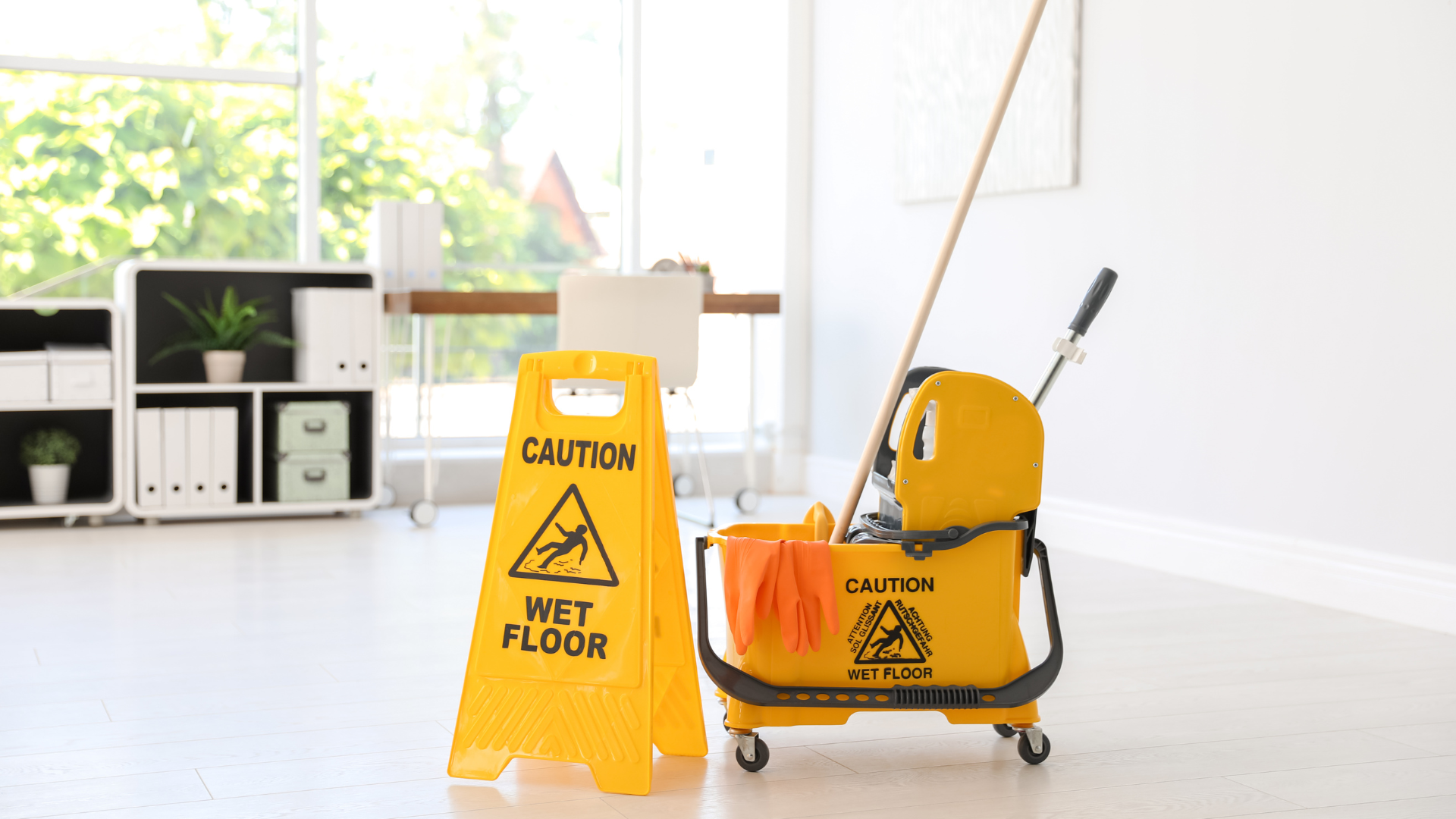 Yellow floor-cleaning machine beside a person mopping a wet indoor floor.