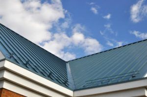 Blue metal roof with a clear blue sky and clouds in the background.