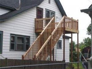 A white house with a wooden deck and stairs