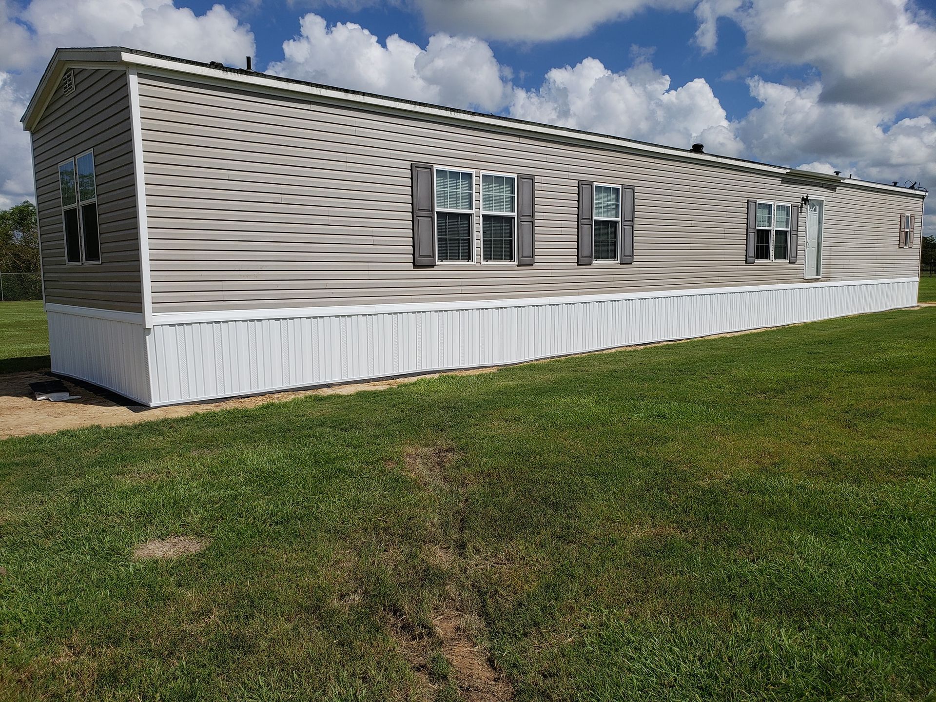 A mobile home is sitting in the middle of a grassy field.