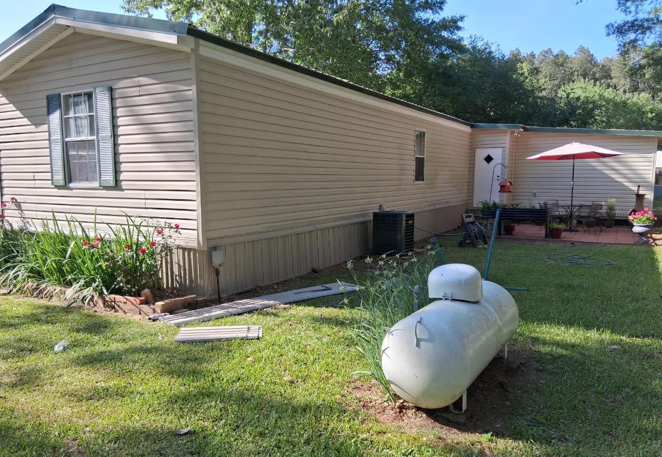 A mobile home with a propane tank in front of it.
