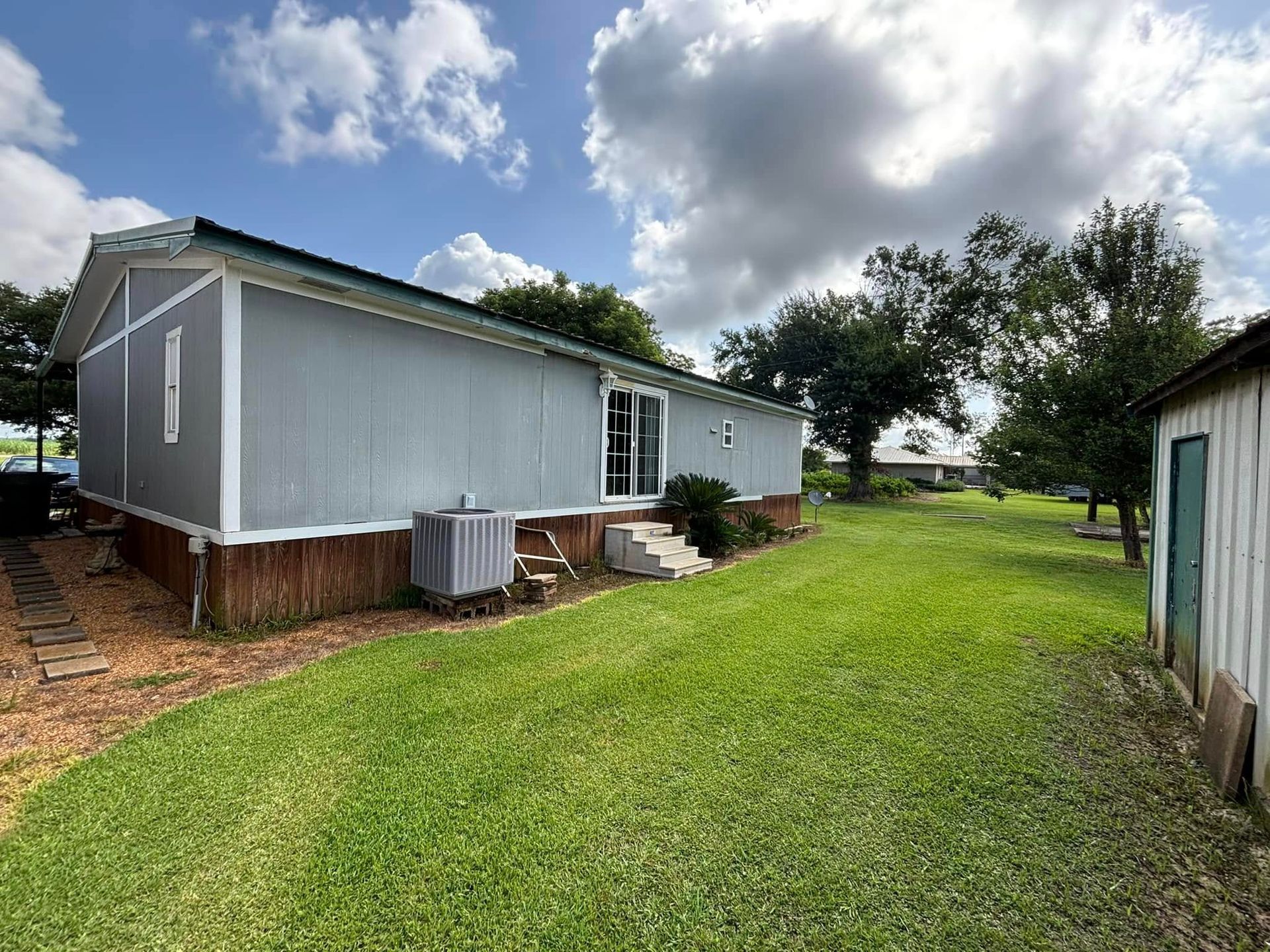 A mobile home is sitting in the middle of a lush green field.