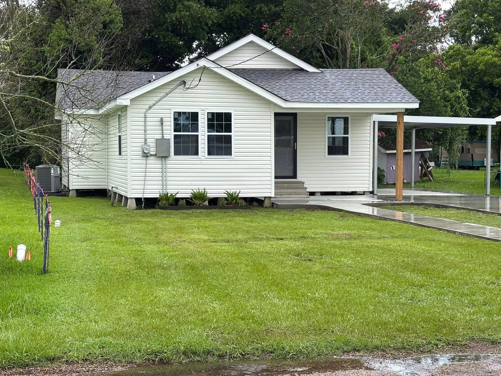 A small white house with a lush green lawn in front of it.