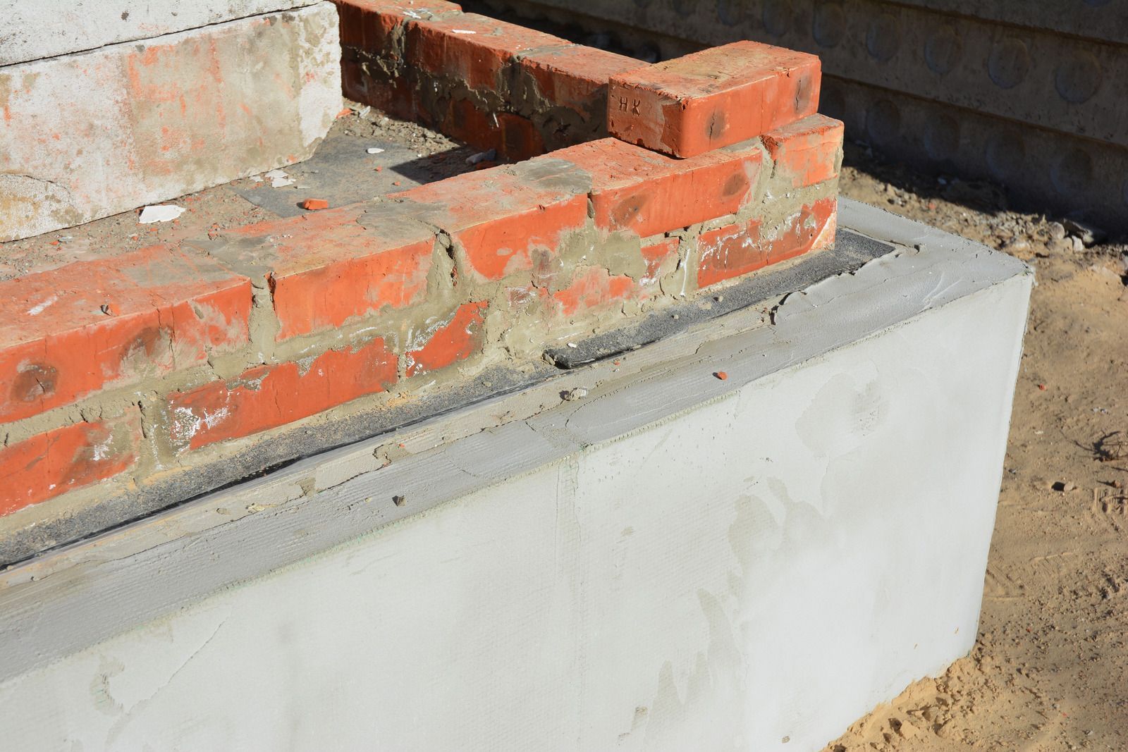A brick wall is being built on top of a concrete block.
