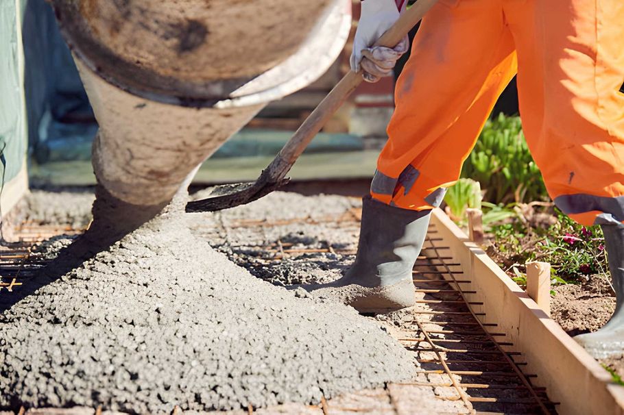 Construction worker pouring wet concrete onto a sidewalk form