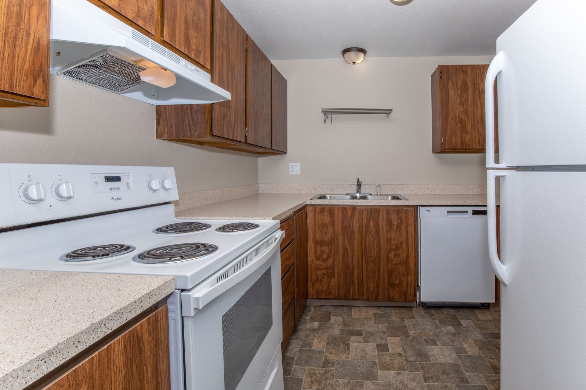 A kitchen with a stove , refrigerator , dishwasher and sink.
