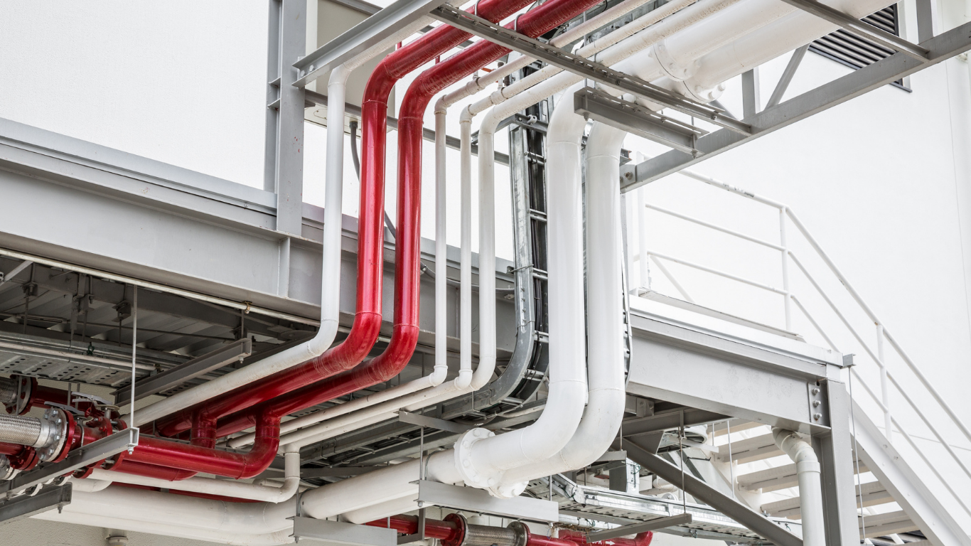 Red and white pipes running along a metal structure, likely industrial or commercial setting.