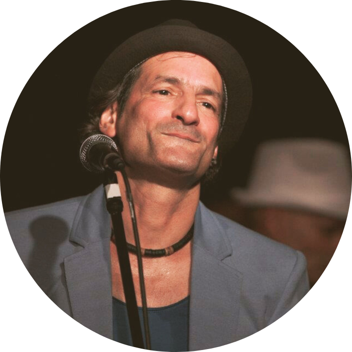 Ein Mann mit Hut singt in ein Mikrofon