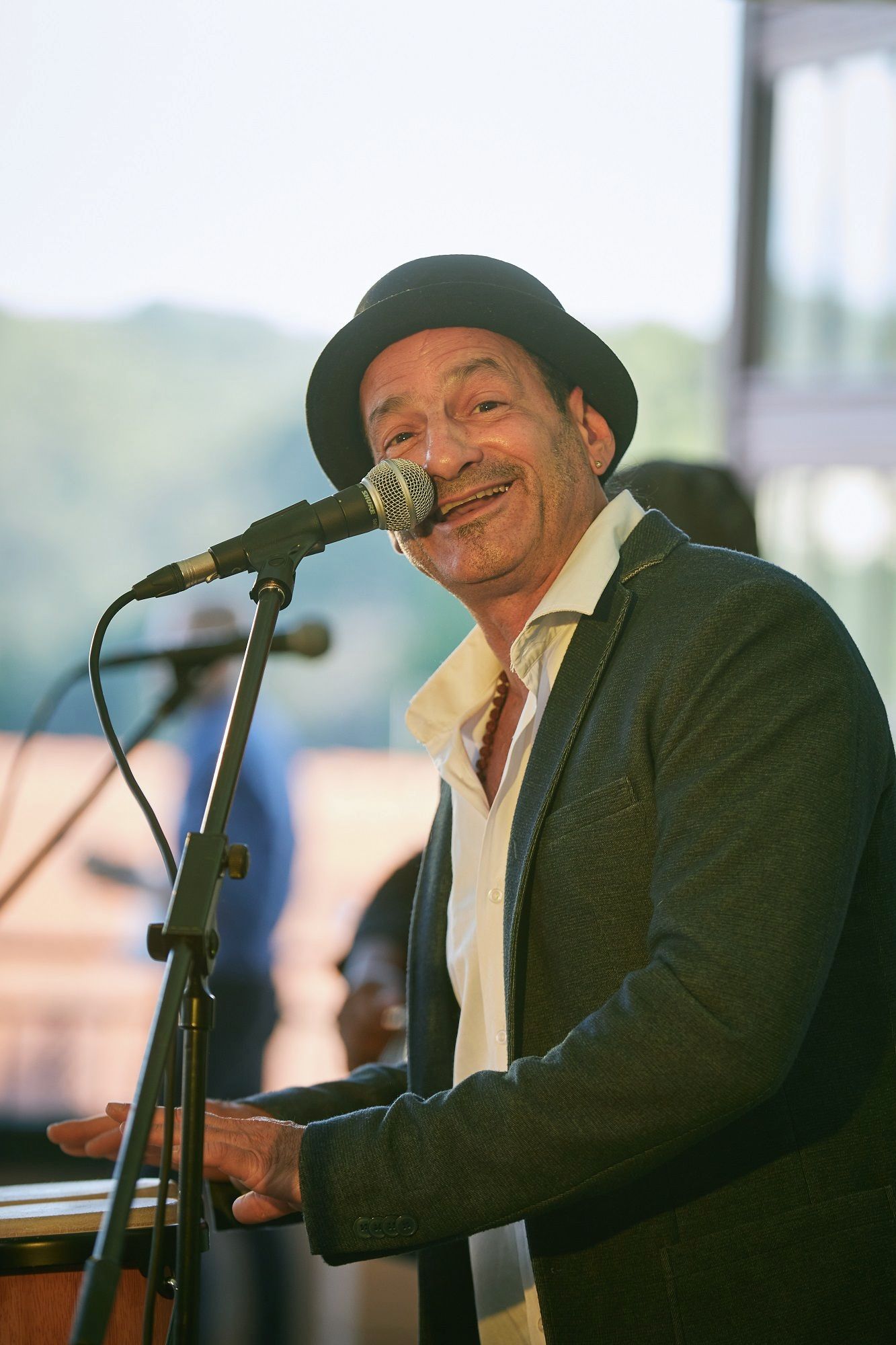 Ein Mann mit Hut singt in ein Mikrofon