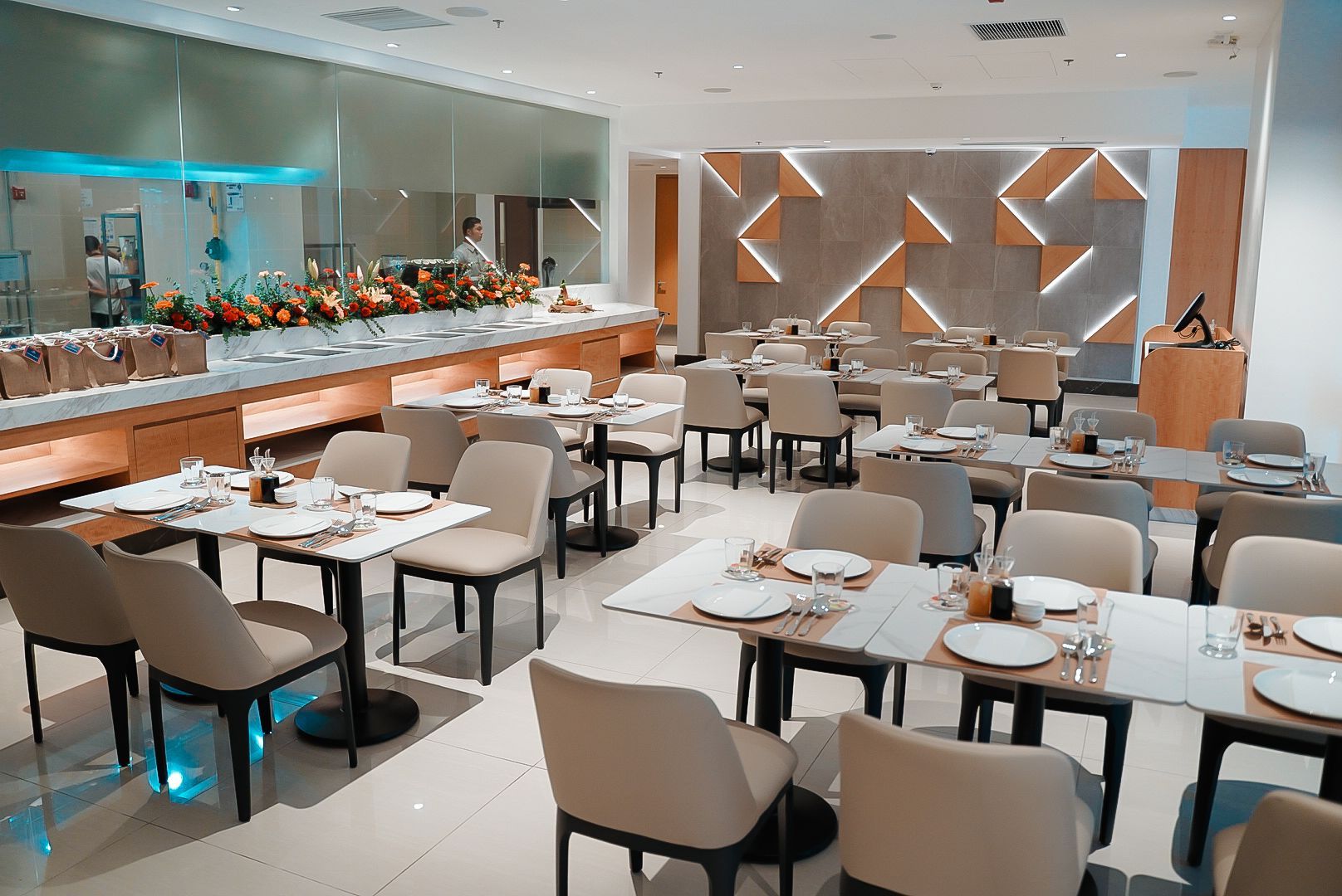 Restaurant interior with tables, chairs, buffet, and decorative wall.