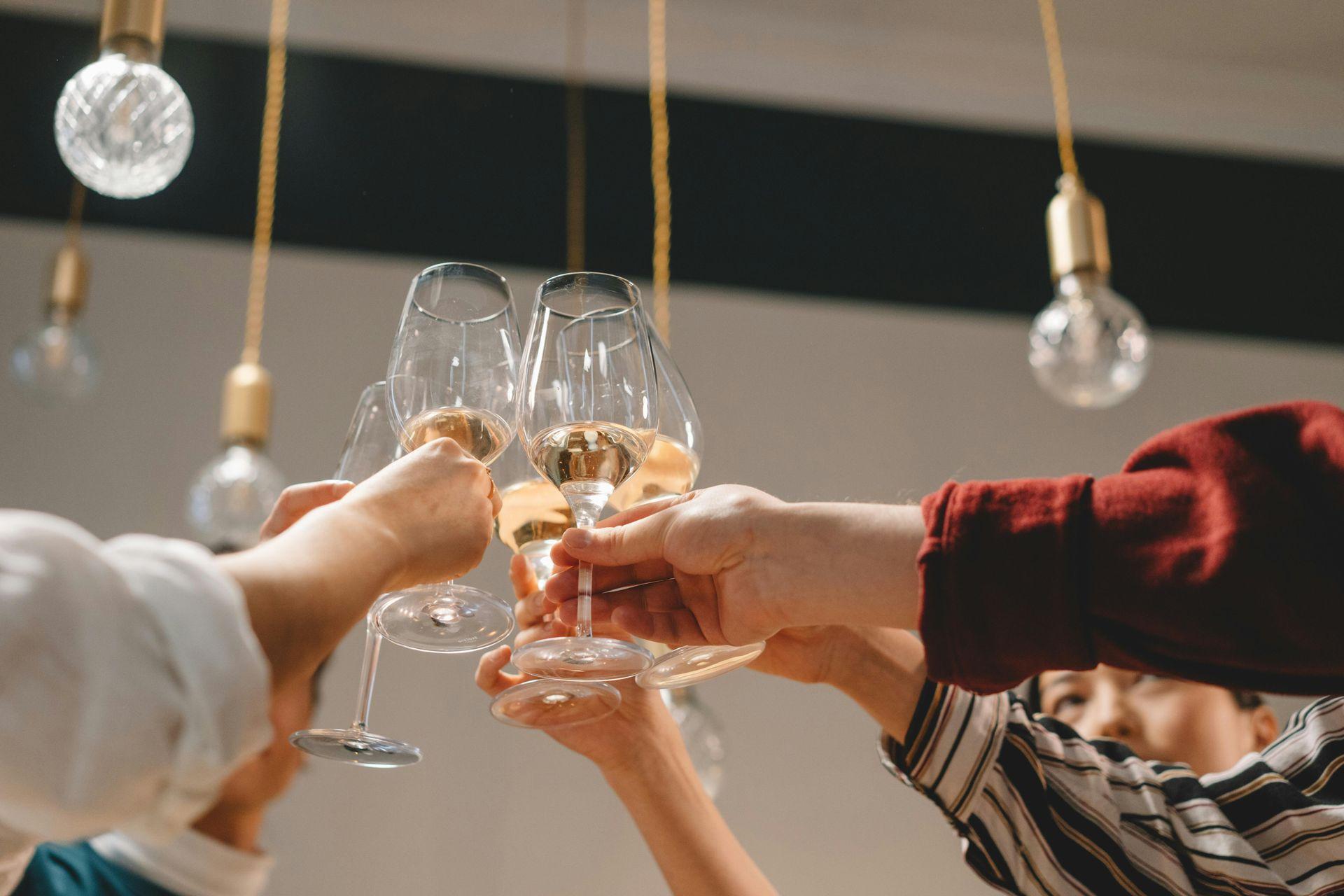 People toasting with champagne flutes under hanging lights.