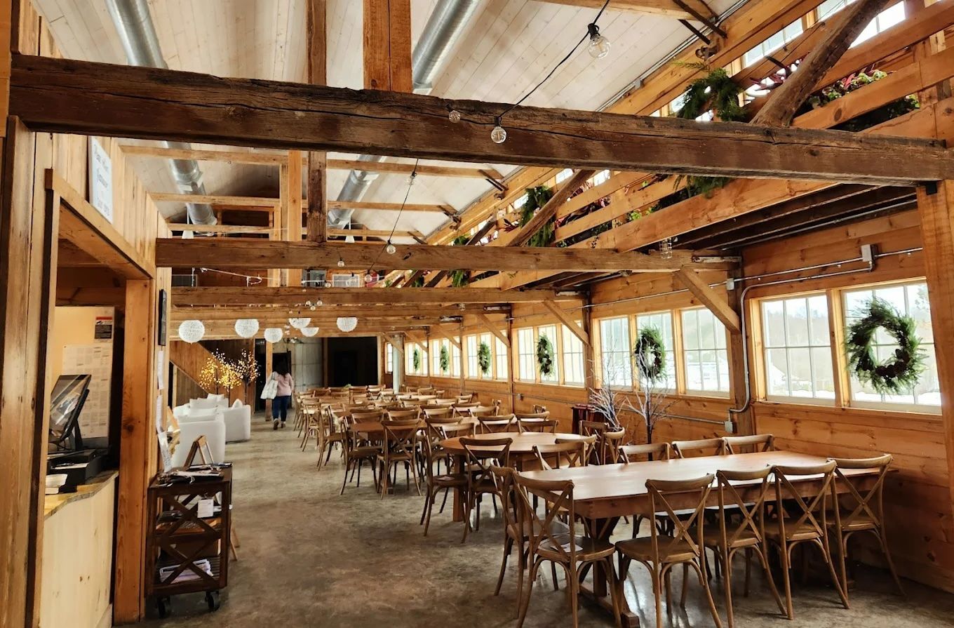 A large room filled with tables and chairs in a barn
