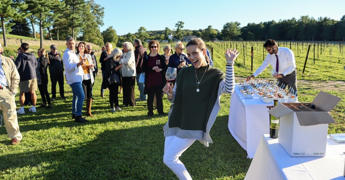 A woman is dancing in front of a group of people in a vineyard.