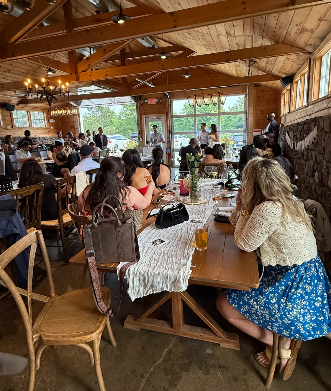 People seated at tables in a rustic wooden restaurant with exposed beams and large windows.