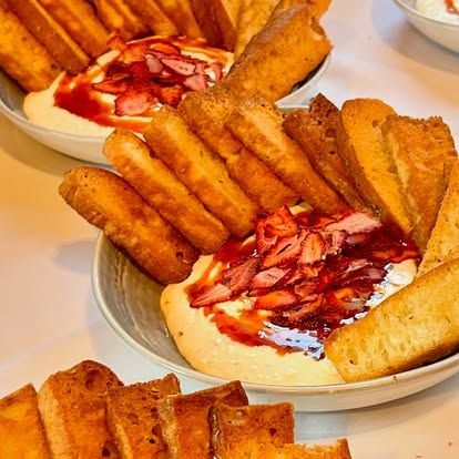 Dessert bowls topped with sliced strawberries and surrounded by biscotti sticks