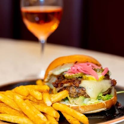 Burger and fries on a plate with a glass of rosé in the background