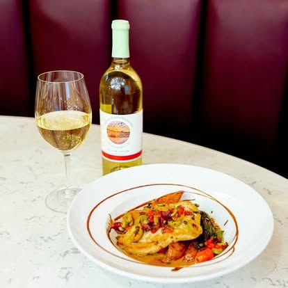 Wine glass and bottle beside a plated pasta dish on a restaurant table