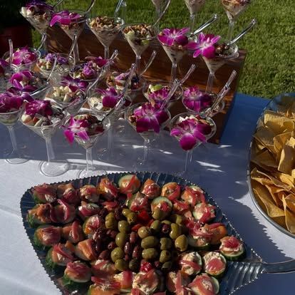Outdoor dessert table with chocolate-dipped strawberries, grape skewers, and gold-wrapped treats