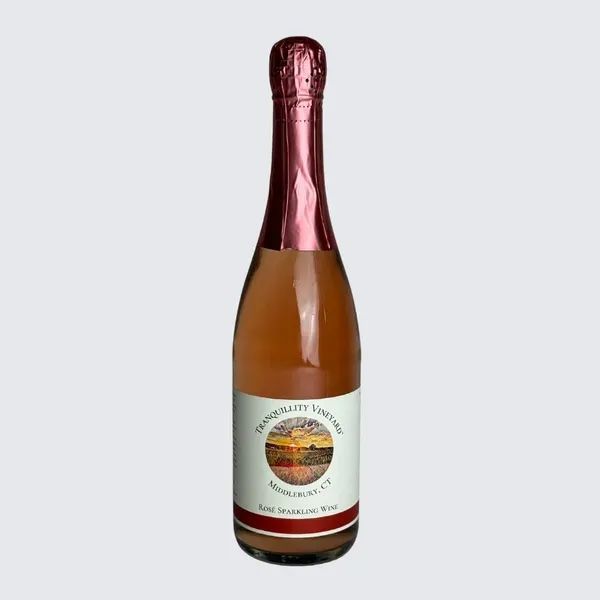 Bottle of sparkling rosé wine with a pink foil top and white label on a light background