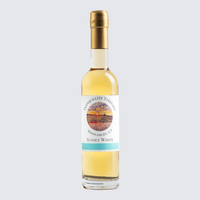 Bottle of yellow liqueur with a gold cap and white label on a light gray background