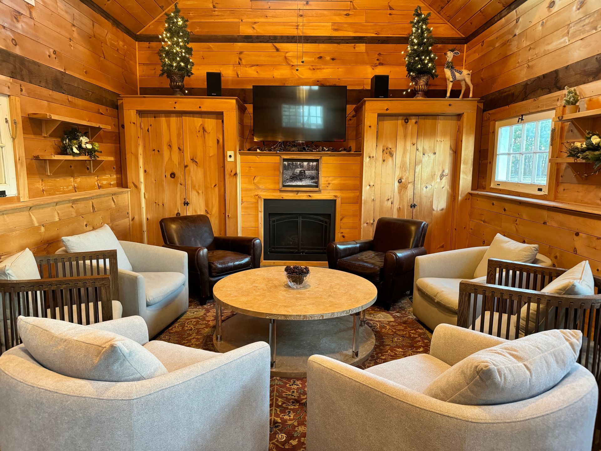 Cozy log cabin living room with fireplace, TV, and round seating area around a coffee table.