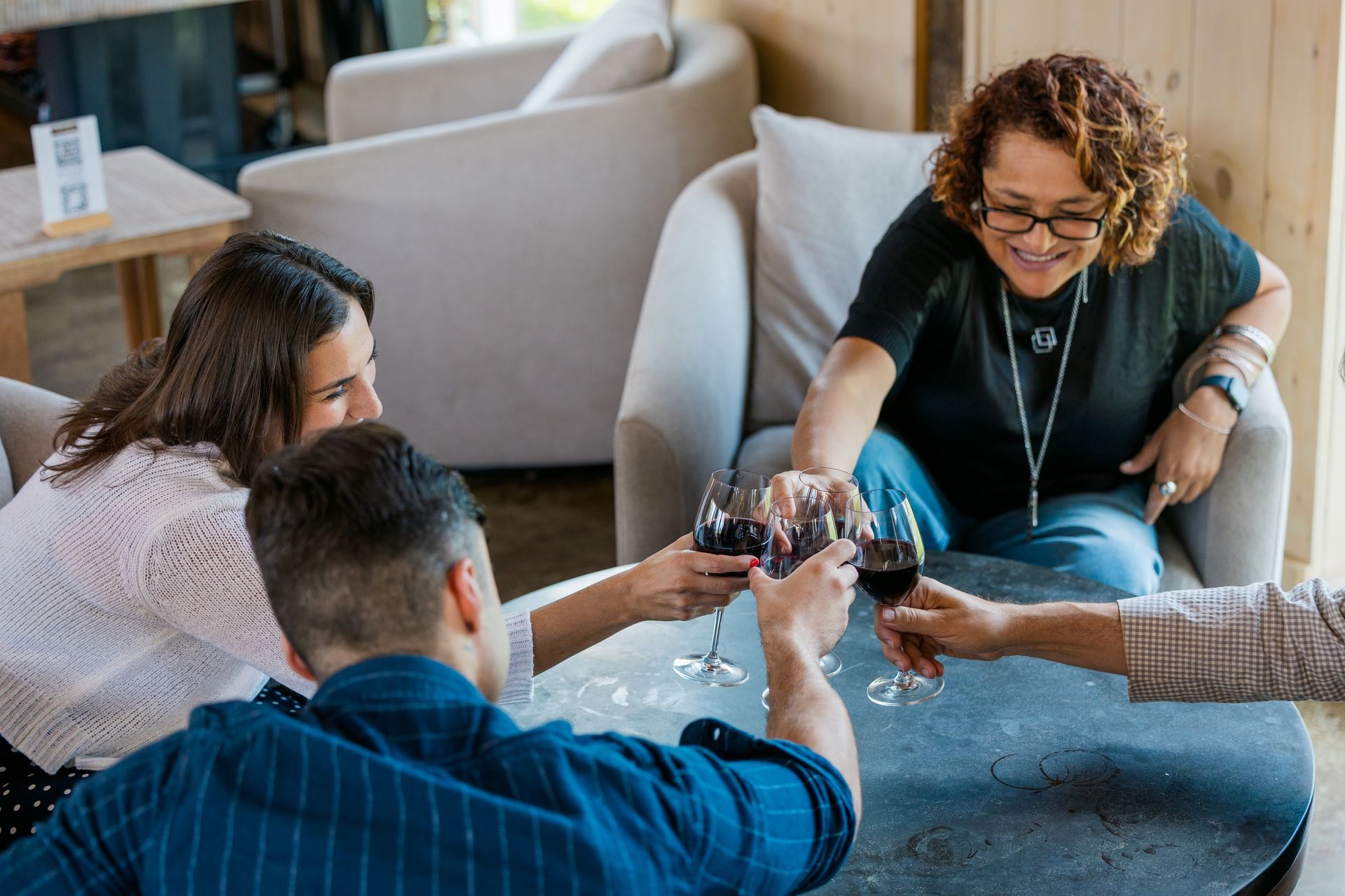 People clinking glasses in a cozy living room, smiling and toasting together
