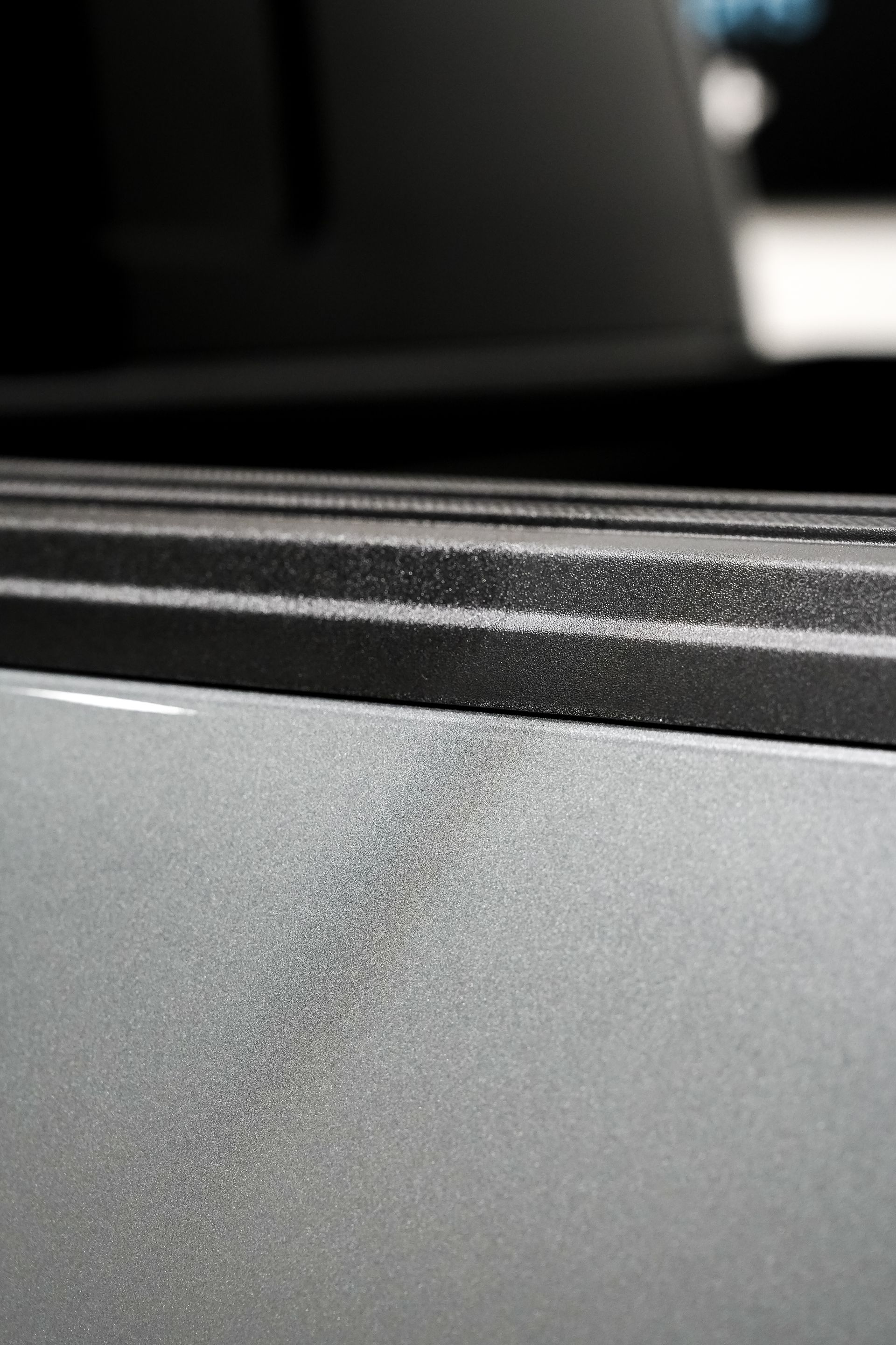 Close-up of a gray textured surface with a black ridged edge and blurred dark background